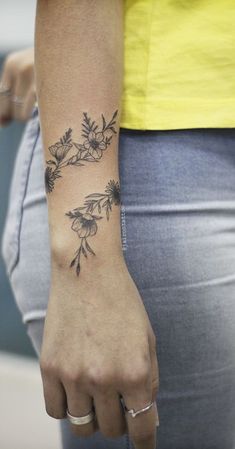 a woman's hand with a flower tattoo on her left wrist and the other arm