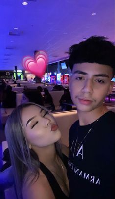 a young man and woman are posing for a photo in a bowling alley with neon lights behind them