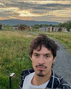 a man standing in the middle of a road with houses behind him and grass on both sides