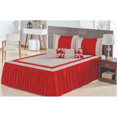 a bed with red sheets and pillows on top of it, next to a night stand