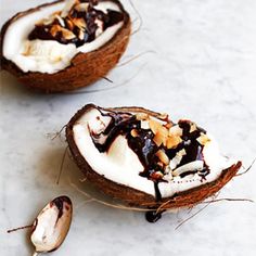 two coconuts with whipped cream and nuts on them sitting on a marble counter top