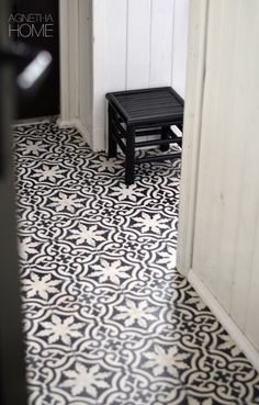 a black and white tiled floor in a room with a small stool next to it