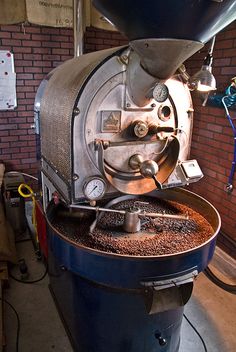 a machine that is sitting on top of a blue barrel in a room with brick walls