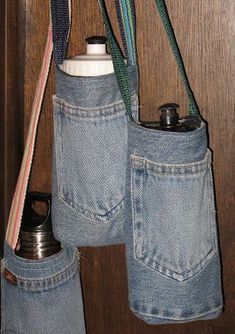 two blue jeans hanging from the side of a wooden door with metal flasks in them