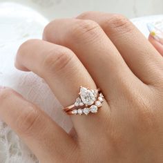 a woman's hand with a diamond ring on top of her finger and the other hand holding an engagement ring