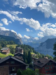 some houses and mountains under a cloudy blue sky