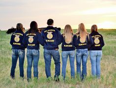 a group of people standing in a field with their back to the camera wearing blue jackets