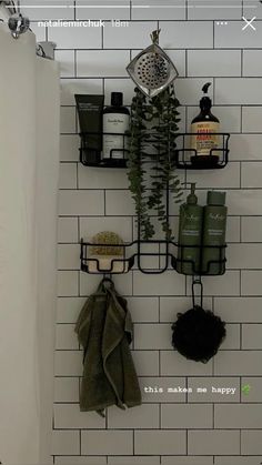 a white tiled bathroom with black metal shelfs on the wall and green plants growing out of it