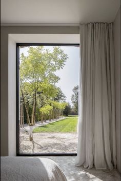 a bedroom with a large window that looks out onto the yard and tree lined area