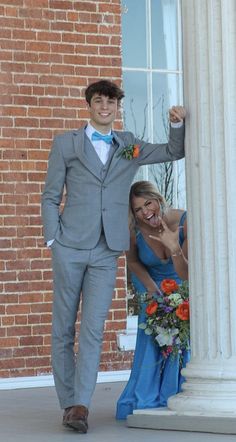 a man in a suit and tie standing next to a woman wearing a blue dress