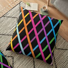 a black floor pillow with multicolored lines on it and a cup of coffee next to it