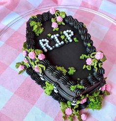 a heart shaped cake with flowers and letters on it sitting on a checkered tablecloth