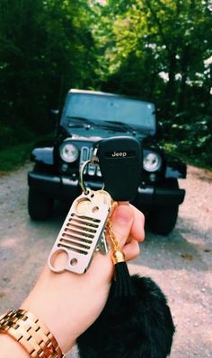 a person holding a car key chain with a jeep in the background