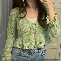 a woman taking a selfie in front of a mirror wearing a green cardigan