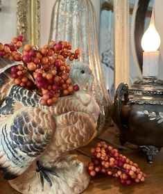 a turkey figurine sitting on top of a wooden table next to a candle