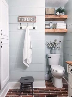 a white toilet sitting in a bathroom next to a wooden shelf with towels on it