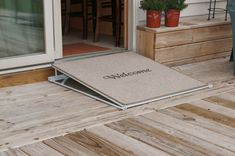 a welcome mat on the front porch of a house with chairs and potted plants