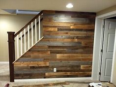 an unfinished room with wood planks and white stair case in the corner, next to a