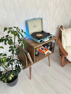 a record player sitting on top of a wooden table next to a potted plant