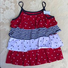 Top Is 20” Long From Top Of Shoulder (Top Of 6” X3/8” Spaghetti Straps). Chest Measurement: 29” Around Measured Underarms. Armholes: 16” Around; Scoop Neckline: 30” Around. Four 100% Cotton Knit 4.5” Wide Gathered Ruffles: Red With White Stars, White With Navy Stars And Navy & White Stripes On A Red Polyester Body. Machine Wash And Dry. Size L = 10/12. Playful Red Tops For Summer, Red Tops For Spring Playtime, Fun Red Tops For Playwear, Playful Red Summer Tops, Fun Red Top For Playwear, Multicolor Ruffled Tops For Playwear, Red Sleeveless Top For Playwear, Red Cotton Top For Playtime, Red Cotton Tops For Playtime