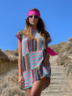 a woman in a colorful crochet dress and headband standing on some steps