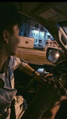 a man driving a car at night with his hands on the steering wheel