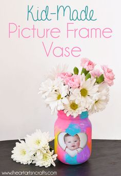 a vase with flowers in it sitting on a table next to a sign that says, kid - made picture frame vase