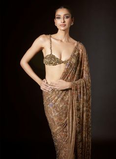 This stunning gold pre-stitched sari features intricate hieroglyphic crystal embellishments. Paired with a blouse adorned with large stones, it exudes opulence and sophistication, making it a perfect choice for special occasions or formal events. The combination of traditional sari craftsmanship with contemporary design elements creates a timeless and captivating ensemble that is sure to turn heads wherever you go. Festive Gold Embellished Pre-draped Saree, Gold Pre-draped Saree For Reception, Gold Pre-draped Saree For Diwali Reception, Fitted Gold Pre-draped Saree For Festive Occasions, Elegant Gold Pre-draped Saree For Festivals, Gold Pre-draped Saree For Reception And Festive Occasions, Traditional Hand Embellished Pre-draped Saree For Diwali, Traditional Hand Embellished Silk Pre-draped Saree, Gold Embellished Choli