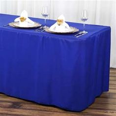 two plates with silverware are on a blue table cloth that is draped over it