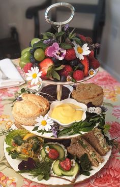 three tiered trays filled with food on top of a floral covered table cloth