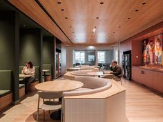 two people sitting at tables in an office with wood paneling on the walls and ceiling