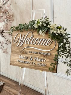 a wooden welcome sign with greenery on it