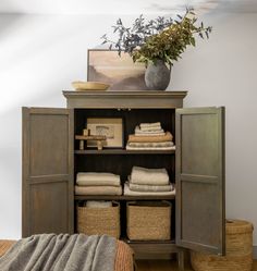 an open cabinet with towels and baskets in it