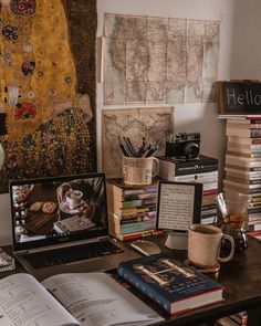 an open laptop computer sitting on top of a desk next to books and other items