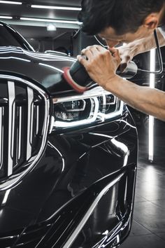 a man polishing the front grille of a black car with a red and white stripe