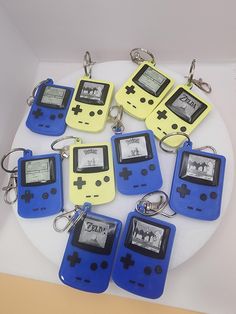 six gameboy keychains are arranged on a white plate with blue and yellow tags