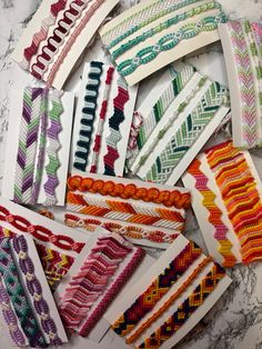 many different colored bracelets laid out on a marble counter top, all with beading