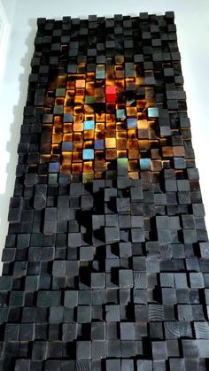 an artistic piece of art made out of wood and colored glass tiles on the wall