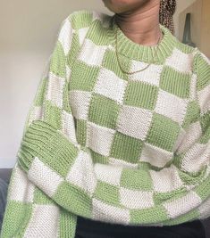 a woman wearing a green and white checkered sweater with her hands on her hips