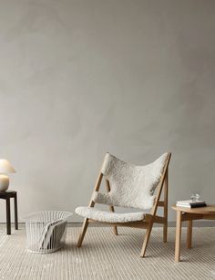 two chairs and a table in an empty room with white walls, one chair is upholstered on the floor