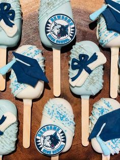 blue and white cake pops decorated with graduation caps and tassels on wooden sticks