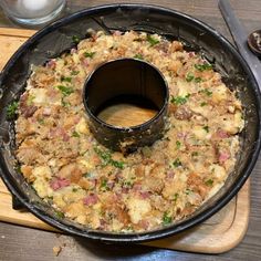 a pan filled with food sitting on top of a wooden cutting board