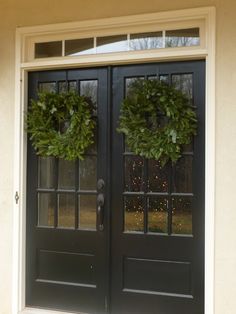 two wreaths on the front door of a house