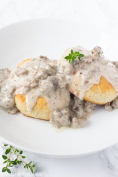 two biscuits covered in gravy on a white plate