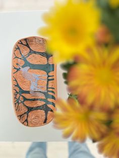 a vase with yellow flowers in it next to a skateboard