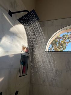 a shower head with water coming out of it's side and windows in the background