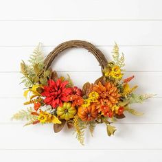 a wreath with flowers and leaves hanging on a wall