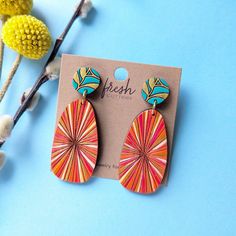 a pair of colorful wooden earrings sitting on top of a card