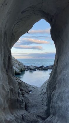 the inside of a cave with water and rocks on either side, looking out to sea