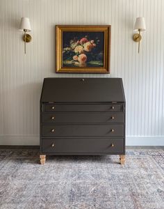 a painting on the wall above a chest of drawers in a room with striped walls